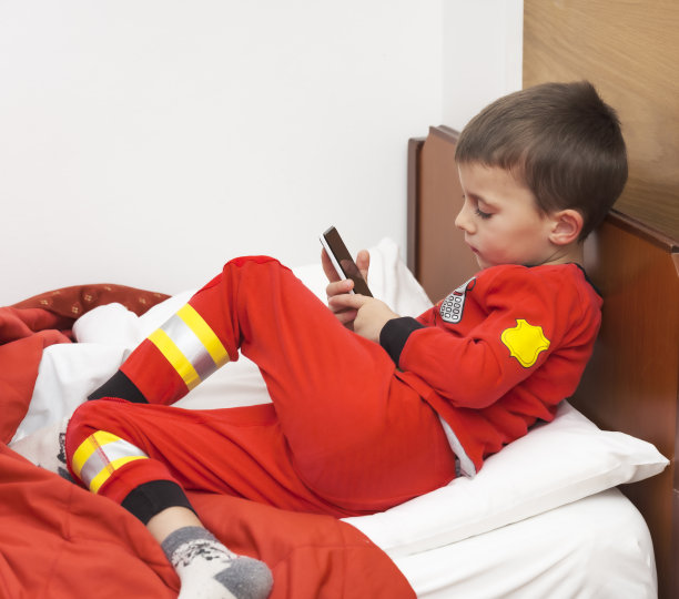 宝宝睡觉前在床上玩手机。图片下载