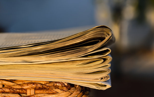 在傍晚阳光下，几份日报躺在一张柳条桌子上的特写图片下载