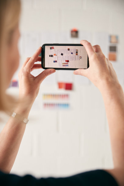 女设计师用手机在墙上拍摄时装设计的照片图片下载