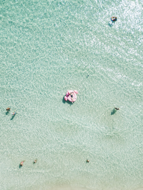 年轻性感的女孩在黑色泳衣躺在充气的粉红色火烈鸟在蔚蓝的海水，游泳，日光浴放松在蓬塔意大利火腿意大利马尔代夫普利亚意大利海滩。夏天的假期图片下载