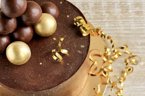 有金色装饰的巧克力生日蛋糕。假日、庆典、时尚、简约的概念。图片下载