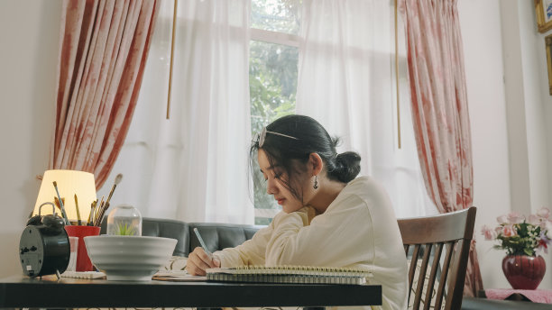 亚洲少女手绘和绘画她的艺术在客厅。她用笔记本电脑和朋友视频通话，同时用水彩和画笔在白纸上创作艺术项目，形成她的想象。家，艺术和手工艺概念。图片下载