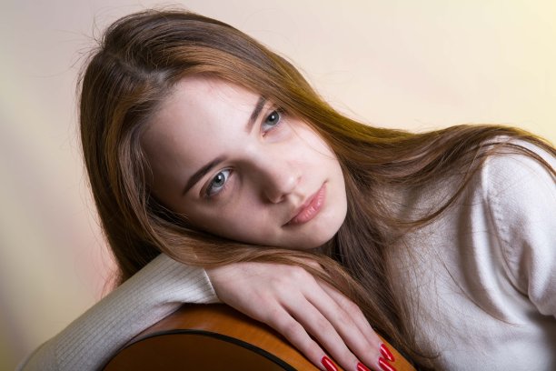 一个拿着吉他的小女孩的肖像。情感的概念。照片上的背景是霓虹色的粉黄色。图片下载