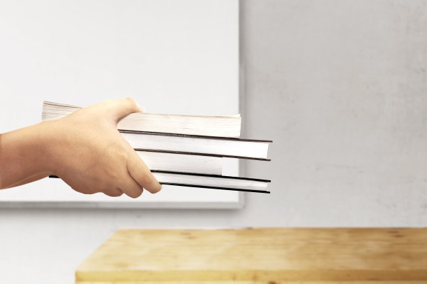 手拿着一堆书，背景是白板图片下载