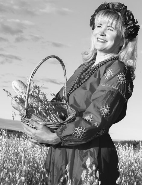 一个金发女孩的肖像。一个女孩提着柳条篮子站在燕麦地里。篮子里有一个面包卷和面包。黑白照片。图片下载