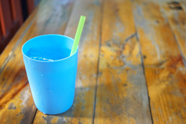 木桌上放着蓝色的冰水塑料玻璃杯图片下载