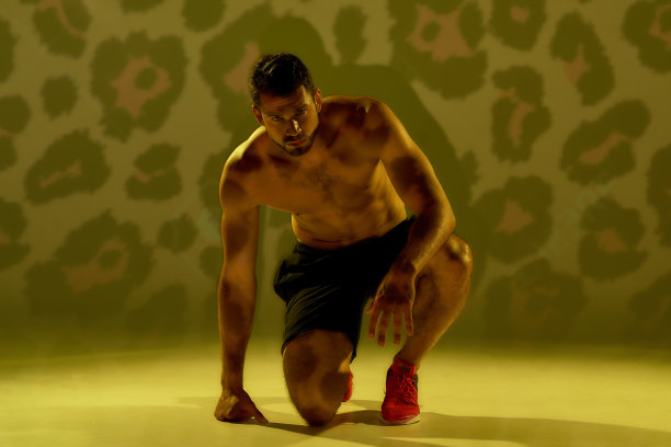 你所需要的就是跑。年轻的肌肉发达的白人男子站在开始的位置，看着相机，准备跑孤立的黄色猎豹背景图片下载