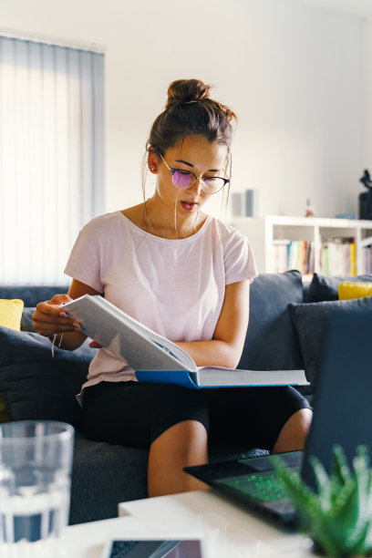 女女孩读大书学习为学院或学校考试-女人在家里沙发上准备考试学习在夏天-教育理念真实的人图片下载