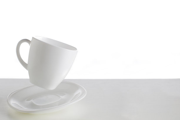 白色背景上的白色杯碟。跳杯。在白色背景上飞行的盘子。白色背景上的白色盘子图片下载