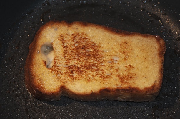 这是一张在黑色煎锅上用黄油煎过的一片面包上的面包丁的艺术照片图片下载