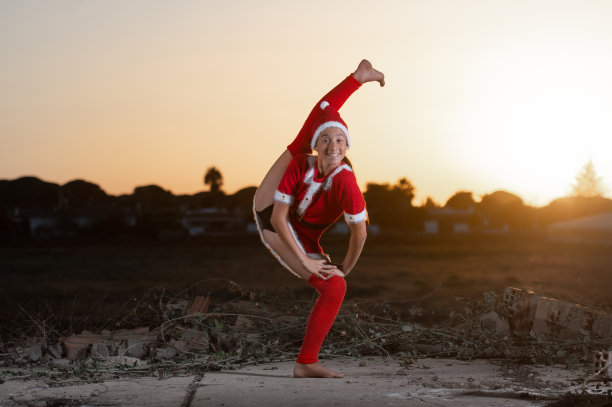 年轻女孩穿着圣诞老人的衣服表演艺术体操图片下载