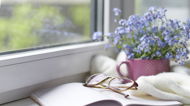 白色温暖的格子毯子和笔记本，眼镜放在木制的乡村长椅上。照片色调，选择性聚焦。温馨的家居静物:窗台上盛开着温暖格子图案的春花图片下载