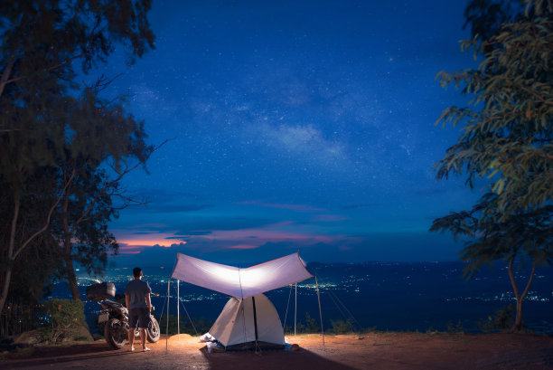 一个露营帐篷和摩托车在日落下在夜空下发光户外露营图片下载