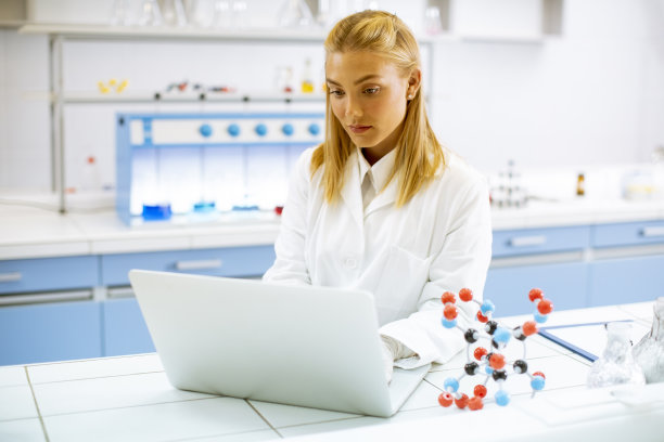 穿着白大褂的女研究员在实验室工作时使用笔记本电脑图片下载