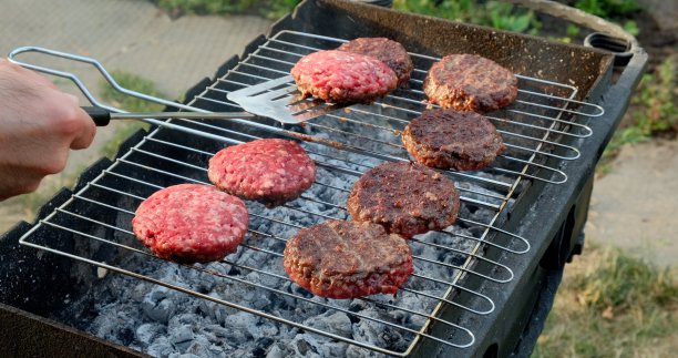 汉堡是在户外制作的。汉堡节日菜单。男人的手抹酱炸汉堡为汉堡图片下载