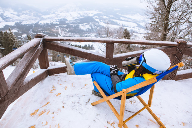 女人在滑雪装坐在椅子上看全景从山顶图片下载