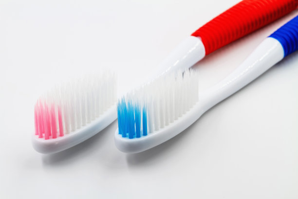 新的红色和蓝色塑料牙刷在白色的背景。特写镜头,有选择性的重点图片下载