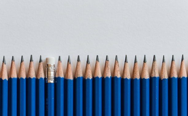 许多新削尖的蓝色铅笔的顶端在白纸上。图片下载