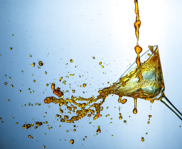 高速液体摄影。大量的酒精饮料小滴从透明的葡萄酒杯里倒出来。水平的形象定位图片下载