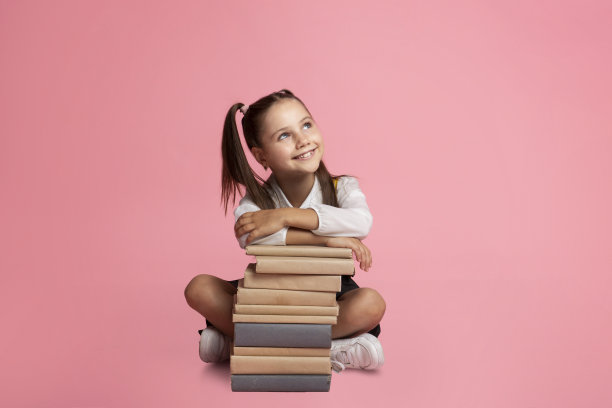 快乐的女学生梦想着，坐在书堆上，看着空荡荡的空间图片下载