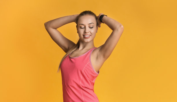 美丽的健身模型与完美的运动身体摆姿势在黄色的背景图片下载