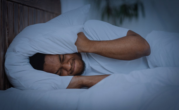 非洲男子用枕头捂耳朵在家失眠图片下载