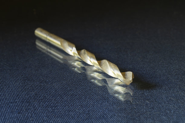 在黑色背景的玻璃桌上的金属上钻孔。图片下载