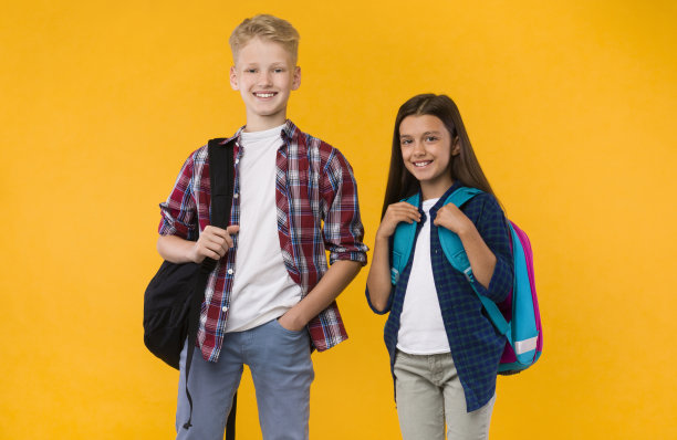 黄色演播室里，背着背包的普通学生站着图片下载