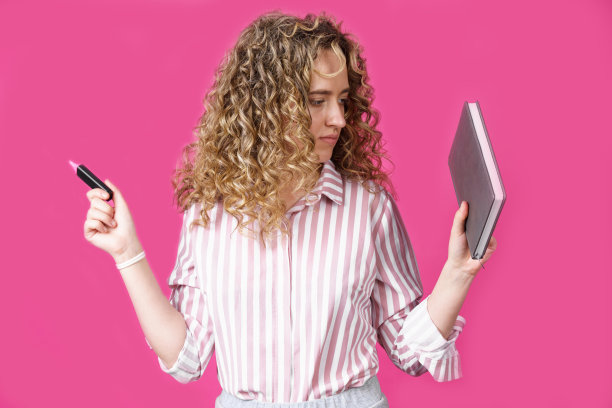 穿着条纹衬衫的时髦女人拿着一本日记本和一支记号笔。图片下载