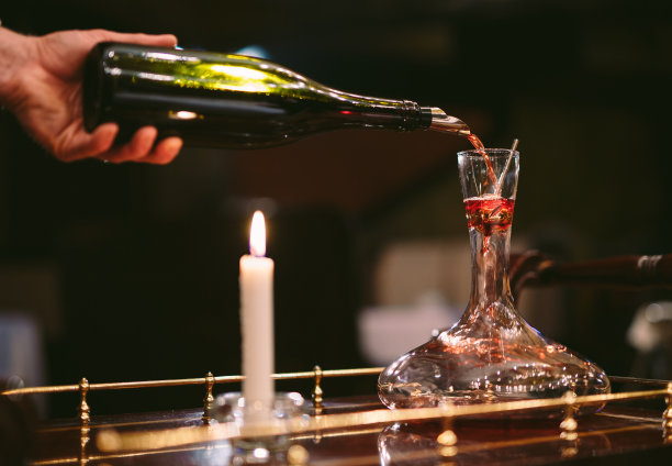 斟酒师把红酒倒进醒酒器图片下载