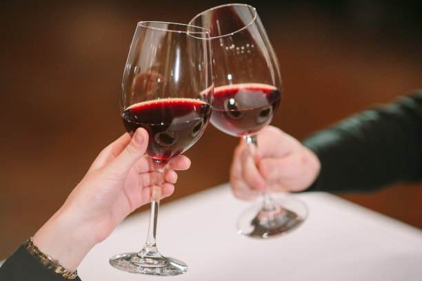 男人和女人在喝红酒。在照片中，特写的手戴着眼镜。图片下载
