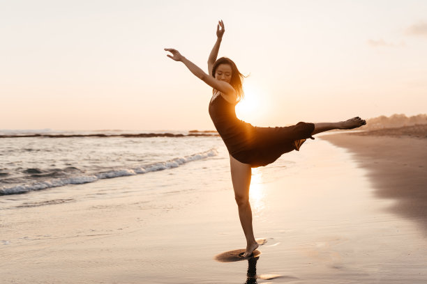 自由的中国女人感觉自由的舞蹈在海滩日落。图片下载
