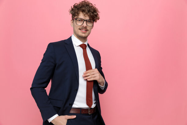 快乐的年轻商人手在口袋和固定领带图片下载