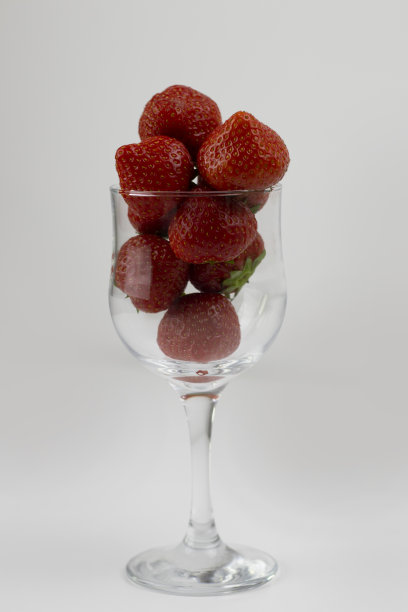 新鲜和成熟的草莓在一个透明的玻璃圆碗孤立在白色的背景图片下载