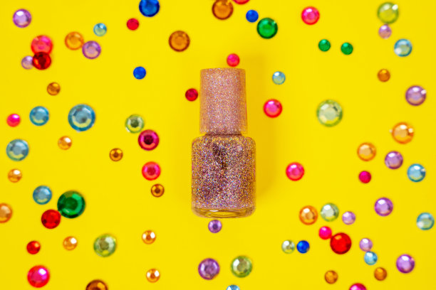 特写瓶身，银色粉色指甲油或亮黄色背景上有彩色亮片和人造镶边图片下载
