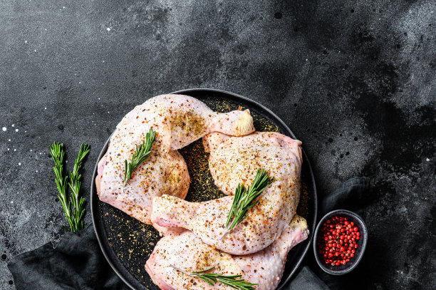 新鲜的生鸡腿、鸡腿放在砧板上加香料，烹饪。黑色背景。前视图。副本的空间。图片下载
