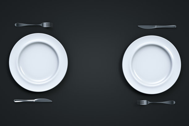 黑色的桌子上放着两套白色的空盘子和刀叉。从以上观点。图片下载