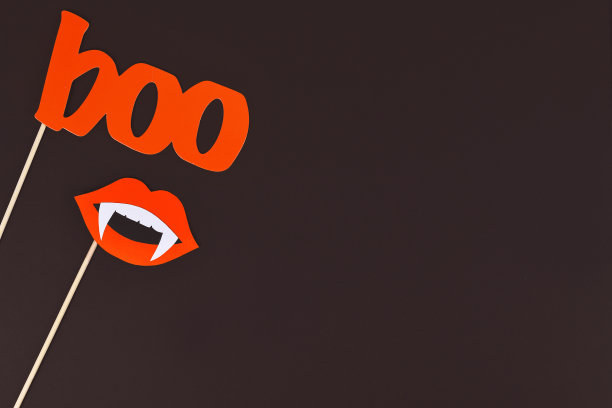 万圣节背景与照片porps棍棒形状的红色单词“boo”和嘴与吸血鬼的牙齿在黑暗的背景与复制空间图片下载