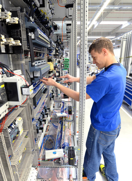 在一家工业公司的一个现代化工厂的机械工程中组装电子元件的年轻学徒图片下载