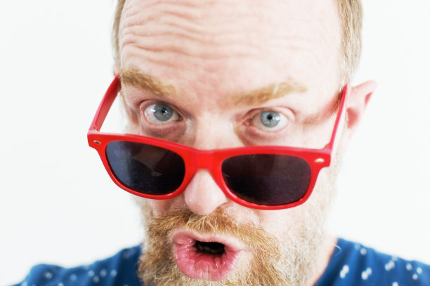 震惊的男子看着他的红色太阳镜，带着幽默的表情图片下载