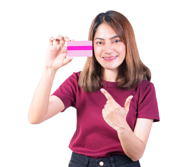 女人的牙套微笑着拿着手指指着信用卡。白色背景的特写图片下载