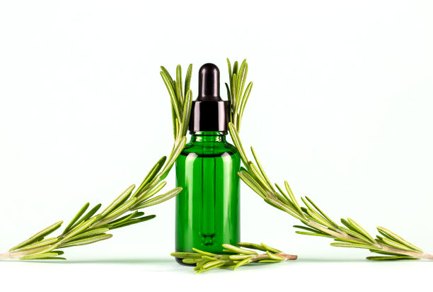 迷迭香精油。滴瓶与天然化妆品油和新鲜迷迭香在一个明亮的背景图片下载
