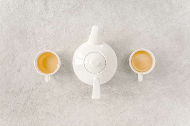 2个白茶杯和茶壶，配绿茶。平躺，俯视图。茶的概念图片下载