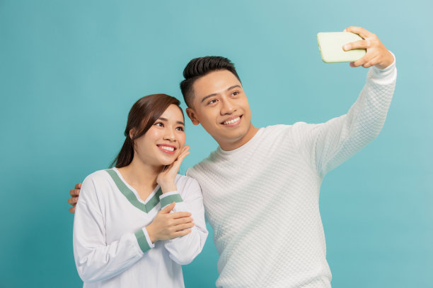 漂亮，浪漫的男孩和女孩在手机上拍照图片下载