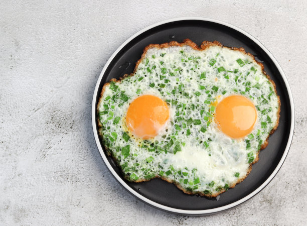 浅灰色背景的圆盘子上放着葱和鸡蛋图片下载