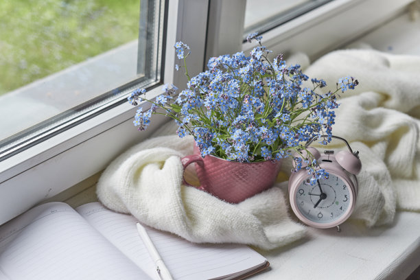 白色温暖的格子毯子和笔记本，眼镜放在木制的乡村长椅上。照片色调，选择性聚焦。温馨的家居静物:窗台上盛开着温暖格子图案的春花图片下载