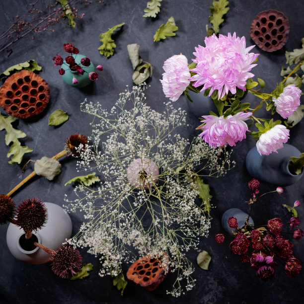 秋天的插花。花瓶里放着一束紫菀花。附近有各种各样的干花和橡树叶。黑暗的具体背景。秋天的概念。生日贺卡。平的。前视图。图片下载