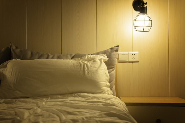 在柔和的灯光下，一个舒适的房间，一个舒适的床和床头柜图片下载