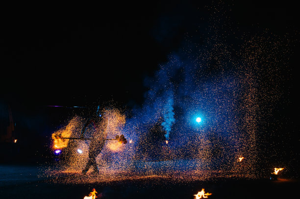 火秀，与火焰共舞，男主用烟花杂耍，在户外表演，在黑暗中画出火红的身影，在夜晚亮起火花。一个穿着西装的男人与火共舞。图片下载