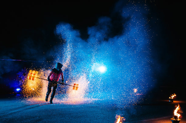 火秀，与火焰共舞，男主用烟花杂耍，在户外表演，在黑暗中画出火红的身影，在夜晚亮起火花。一个穿着西装的男人与火共舞。图片下载